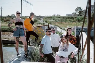 Fashionable group posing in streetwear by an industrial outdoor area.
